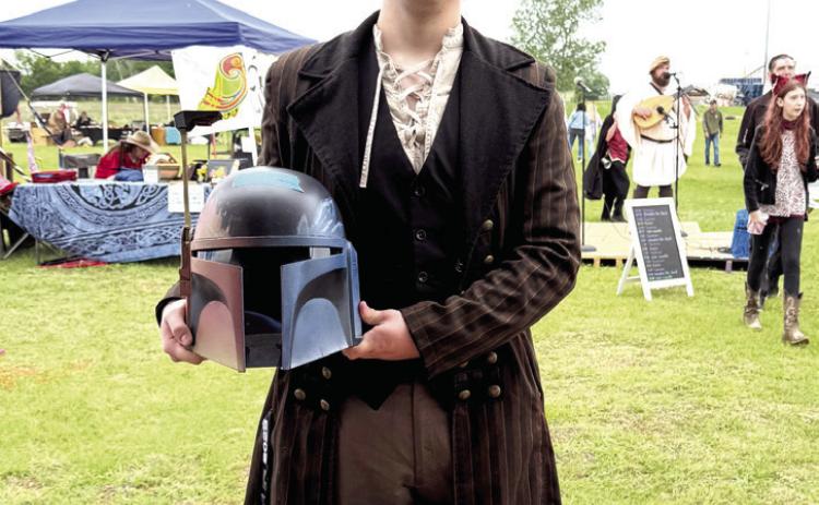Pictured right, Shawnee's Lane Cowan poses with a helmet he made and sold at the Fifth Annual Secret Garden Medieval and Fantasy Faire held behind Shawnee Mall on April 25-26. Cowan says he will gladly participate again next time and bring more inventory, as he almost sold out. All booth owners were required to dress up for the event that brought out quite a crowd. Julie Talton, Countywide &amp; Sun