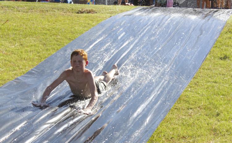 Gunner Billins, 10, of Bethel, cools off on the slip n’ slide, a fund-raiser for the Bethel Little League Cheer program, on Aug. 17. This was one of several booths, including a dunk tank fund-raiser for Bethel Wrestling, at the Bethel High School Blue &amp; Gold Bash held at the football field. Countywide &amp; Sun/Natasha Dunagan