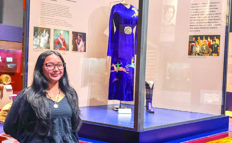 Seminole State College freshman Alivia Wapskineh, 2025 Miss Seminole Nation, stands in front of the Indian Princesses exhibit at the Oklahoma History Center. Photo Provided