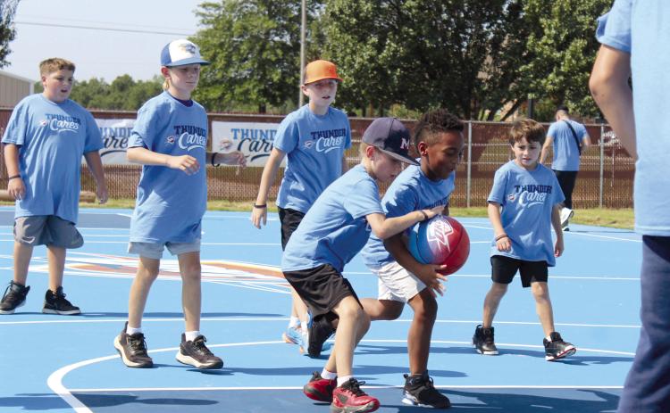 Jeremiah Butts, 7, of Bethel, steals the ball as others watch in a game following the ribbon-cutting for the newly-refurbished Bethel Acres "Thunder" Community Court, located at 18101 Bethel Road, on July 15. The court was resurfaced and repainted, and the nets were replaced, through an OKC Thunder Cares Grant, in conjunction with OG&E. Butts' father said his son has practiced at the court before it was refurbished. Countywide & Sun/Natasha Dunagan