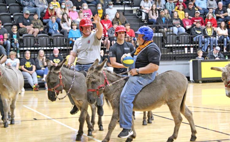 Tecumseh High School Principal Randy Dilbeck goes in for the basket as Tecumseh Firefighter Rhett Banks plays defense and Police Officer Dakota Castle looks on during the first game of the Tecumseh Donkey Basketball event Nov. 6. The Tecumseh school administrators lost to the firefighters and police officers, 2-6. The event was a fundraiser for the Tecumseh Tip In Booster Club and raised $3,500. Countywide &amp; Sun/Natasha Dunagan