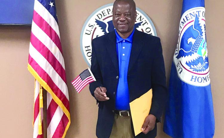 Rev. David Henry, of Shawnee, poses with the U.S. and Homeland Security flags at his naturalization ceremony on April 30. Photo provided.