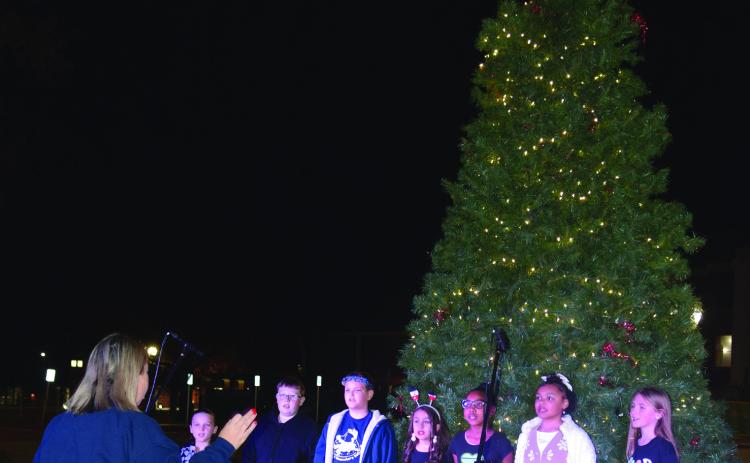 Horace Mann music teacher, Carrie Hathcock, directs carolers performing on the Oval. From left: Zoe Riley, Riyan Wade, Toby Osburn, Kassidee Smith, Andrinee Banks, Promise Spoon and Payton Charvat.