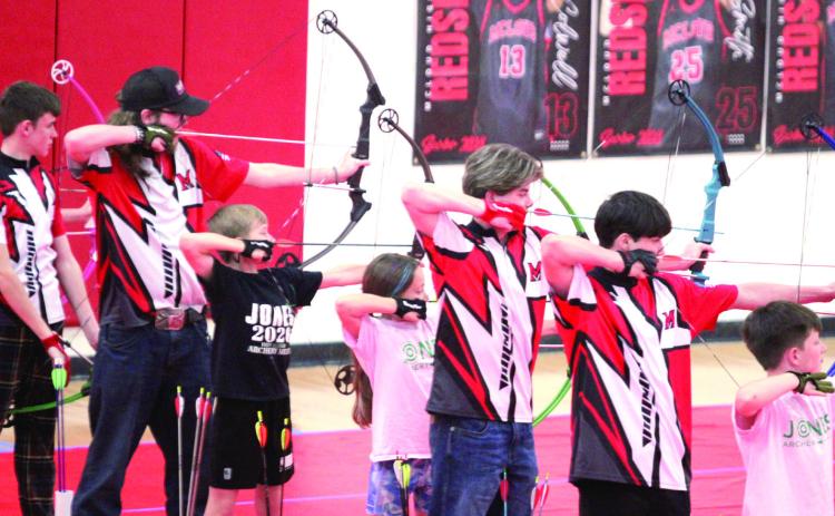 In the red, white and black shirts, from left, Langston Ellison, Dakota Fox, Gunner Moss and Ryan Walls shoot for McLoud High School during the 2026 Oklahoma Centershot Bullseye State Tournament, held at MHS on April 10. Also shown are three archers from Jones. Natasha Dunagan, Countywide &amp; Sun