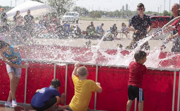 Bud Crawford, of Konawa, far right, and Steve Reese, of Asher, fill a tank and provide some water fun for kids attending the Firefighter Olympics at the Pottawatomie County Free Fair on Sept. 10. File photo