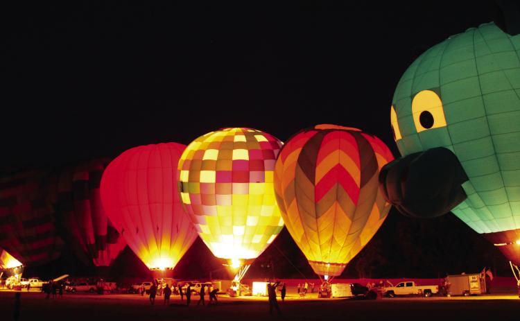 A line of hot air balloons light up on Aug.9, including one shaped like a llama, during the FireLake Fireflight Balloon Festival at the CPN Festival Grounds. As in the past few years, there were 25 balloons from all over the U.S., but they were unable to offer rides this year due to the wind speeds. Photos By Natasha Dunagan, Countywide &amp; Sun