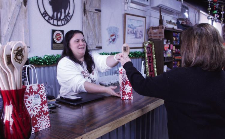 Okie Dokie Mercantile & Co. Owner, Christina Hernandez, hands Gayla Roberts of Prague her purchase, including a wooden spoon Roberts won by spinning a prize wheel. Natasha Dunagan, Countywide &amp; Sun