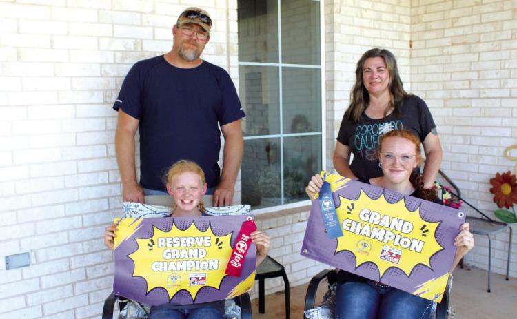 Sisters Callie and Grace Loman, of Bethel, pose with their banners for Reserve Grand Champion and Grand Champion Santa Gertrudis Heifers, which they recently won at the Oklahoma State Fair. Also shown are their parents, Nick and Candace Loman. Countywide & Sun/Natasha Dunagan