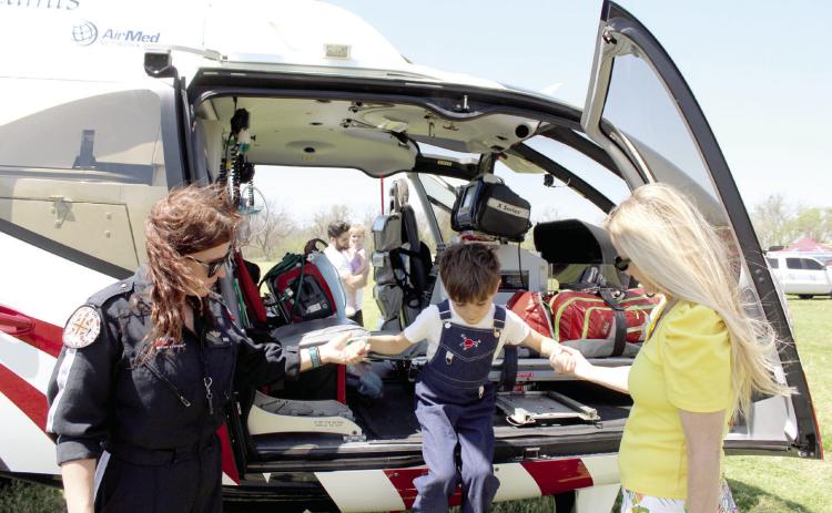 Flight Medic Brittney Little, left, and Jerica Sasse help Jett Sasse, 6, of Edmond, down from the Air EVAC Lifeteam EC130 helicopter, out of Seminole, during the Touch A Truck and Beyond event, held at the Citizen Potawatomi Nation Festival Grounds on April 12. There was also a helicopter from the Air & Marine Operations US Customs & Border Protection at the event.