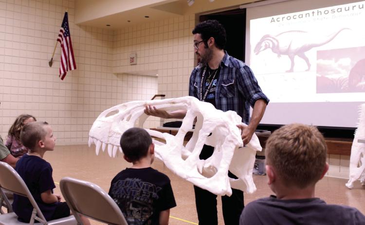 Science Museum Oklahoma Educator Calen Cavallaro holds half of a 3D-printed skull belonging to the Acrocanthosaurus, Oklahoma's State Dinosaur, at the "Dino or Not? The Ultimate Prehistoric Showdown" program at Tecumseh Public Library on July 16. In addition to looking at replica and real fossils, kids could choose paper body parts and create their own dinosaurs. Photos by Natasha Dunagan, Countywide & Sun