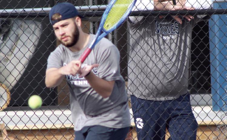 Shawnee senior Bryce Comstock returns the ball, as Coach Tyler Harrison watches, during the Tennis Scrimmage against Tecumseh.