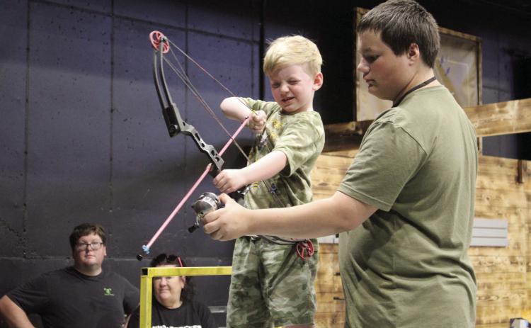 Damian Pearson, 5, of Marlow, is assisted in target bowfishing by Zak McMunn, of Darkwater Adventures in Meeker, during the Outdoor Nation Expo on Aug. 11, 2023 at FireLake Arena. File photo