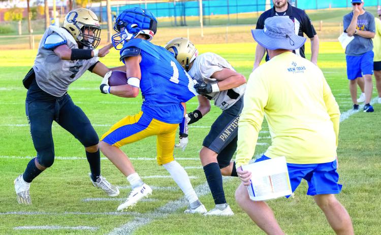 Bethel’s Reagan Curry tries to run the ball around two Okemah players during a scrimmage on Aug. 25, as the referree blows his whistle. Bethel also played Woodland that day. Photo provided by Richelle Treece.