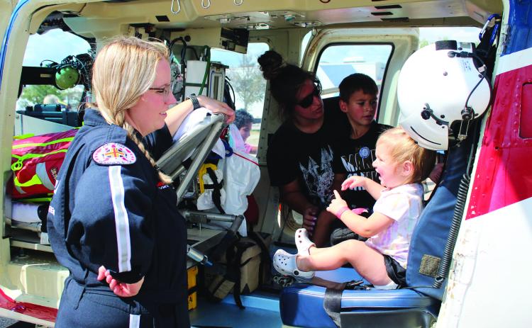 Air Evac Lifeteam Flight Nurse Danielle Siemers, far left, keeps an eye on Tatum Terry, 1, as her mother Jordynn Terry and brother Treyson Terry, 5, all of Shawnee, look at the medical helicopter equipment during Cops n’ Kids on Aug. 27. Countywide &amp; Sun/Natasha Dunagan