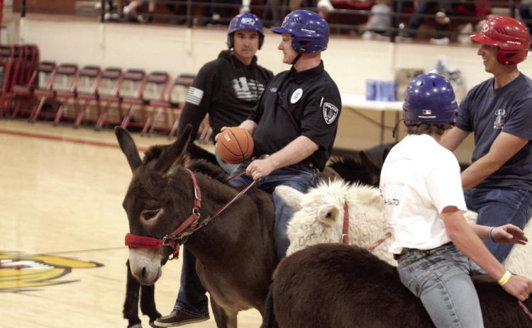 Earlsboro Police Chief Christopher Bayless, with the Hoof Patrol team, looks to pass during the Third Annual Earlsboro Donkey Basketball fundraiser on April 4 at the EHS Gym. Shown, from left, are Anthony Glasgow, Bayless, Bayless's son, Easton Barnes, and firefighter Caleb Inman. See full cutline below.
