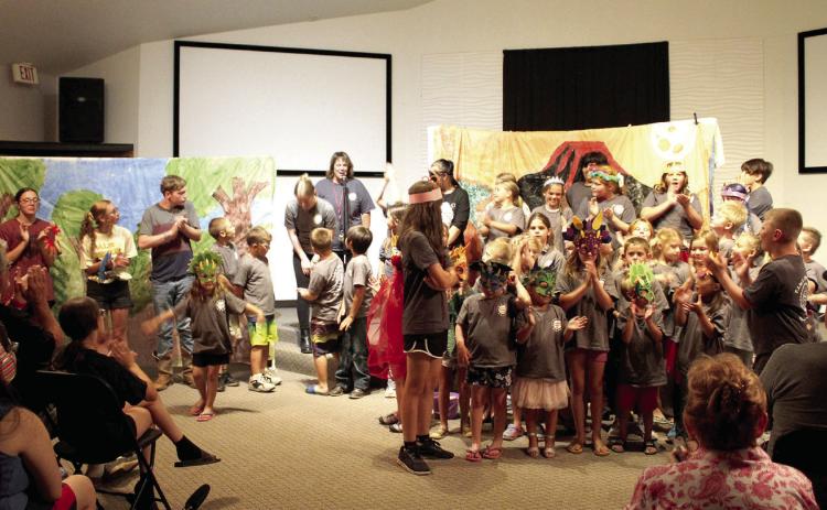 As Macomb Summer School Director Shannon Browning speaks, 58 students applaud their director and theatre teacher Kendra Johnson following their play, "Attack of the Evil Bugs," presented at the Student Center on July 13. The play was written by the students, who also designed and painted backdrops on plastic tablecloths and made fliers. Johnson said the pre-K through fifth-grade students spent the last seven weeks working on the play, and she tried to make the experience fun so they wouldn't lose interest.