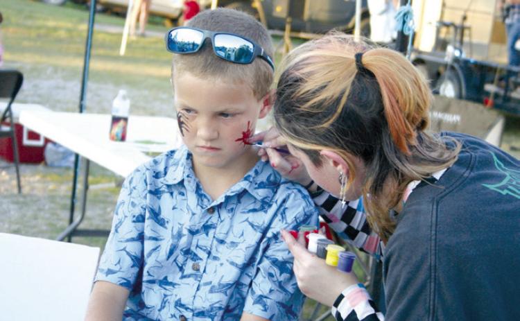 Asher eighth-grader Alice Middleton paints on the face of Everest Headley, 7, of McLoud, during the Second Annual Macomb 21st CCLC Trade Days on Sept. 28. Countywide & Sun/Natasha Dunagan