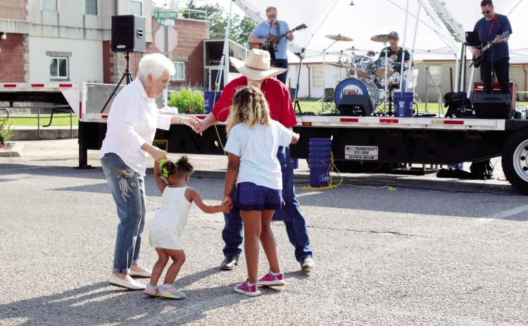 As the band House Special plays, Genesis Robbins, 2, and Zoe Robbins, 8, both of Tecumseh, dance with Rita Yarbrough of Shawnee and Jerry Yarbrough of Sparks during the Mingle on Main Street Block Party on June 8. The Yarbroughs invited the girls to dance with them at the corner of Broadway and Washington in Tecumseh. Countywide & Sun/Natasha Dunagan