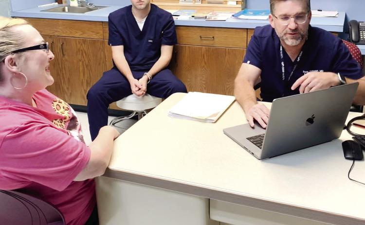 Dr. Scott Stewart talks with Kelly Long, a patient at the Pottawatomie County Volunteer Health Clinic, as his son and medical scribe Parker Stewart looks on, May 11. Stewart also volunteers at the clinic with his other son, Reid, not shown, who screens patients and helps in the pharmacy. Photo provided by Sharon Gerards.