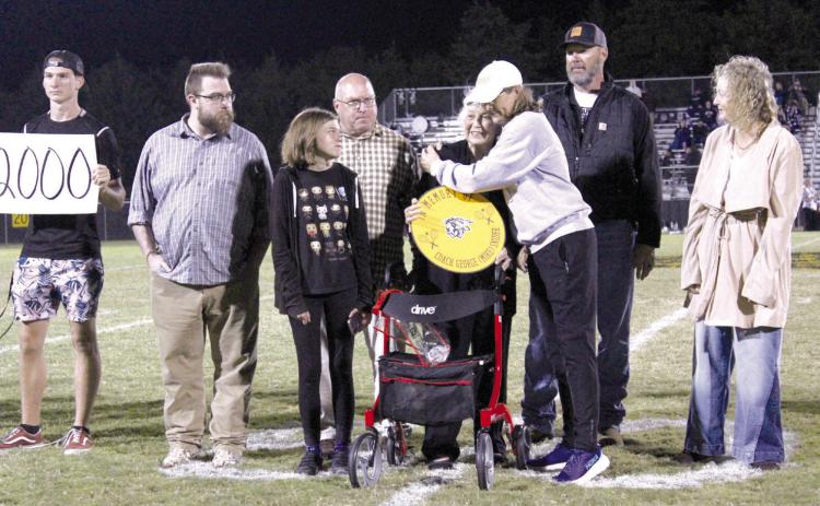 Judy Snider, the wife of late Tecumseh Tennis Coach George “Mike” Snider, gets a hug from current Tennis Coach Jennifer McKnight, as Snider’s sons Greg and Blake and other family members look on. Coach Snider was memorialized with a sign that will hang on the tennis court fence during the Oct. 12 home football game.