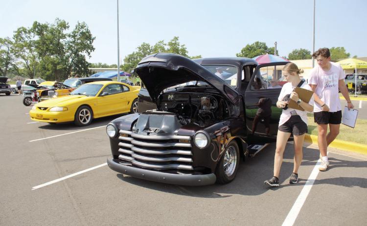 Tecumseh Cheerleaders Addison Taron and David Lawrence, both sophomores, judge a 1949 GMC truck belonging to Larry Higgs of South Rock Creek at the Third Annual Tecumseh High School Cheer Booster Club Car Show on Aug. 26. Higgs said the truck belonged to his late wife, Wailene, who picked out the “Black Cherry” paint before she passed. Countywide & Sun/Natasha Dunagan