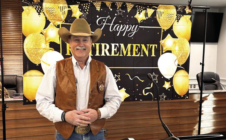 Mike Booth poses in front of his retirement banner during the party held in his honor Dec. 30, 2024. Booth served as Sheriff for 16 years. Countywide &amp; Sun/Suzie Campbell