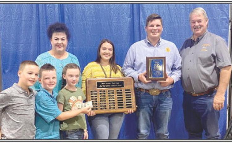 Cooper Kline receives the Ann (Sis) Gilbert award at the 2021 Pottawatomie County Free Fair. The award is presented by the Gilbert family, Randy, Annie Jo, Suzanne, Bryar, Legend and Taycie. Morley Griffith is holding the plaque with all past winners.