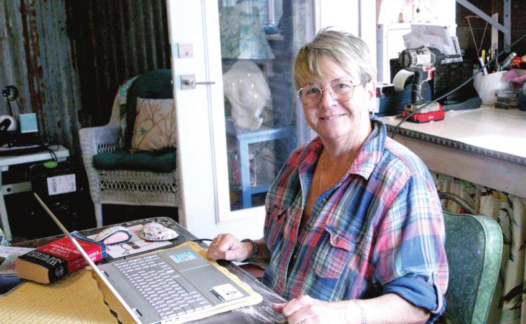 Patti Poteete, writer of the Countywide &amp; Sun’s recurring column, “Sanity’s Last Stand,” poses with the laptop which she writes it on, at her kitchen table. Countywide &amp; Sun/Kendra Johnson