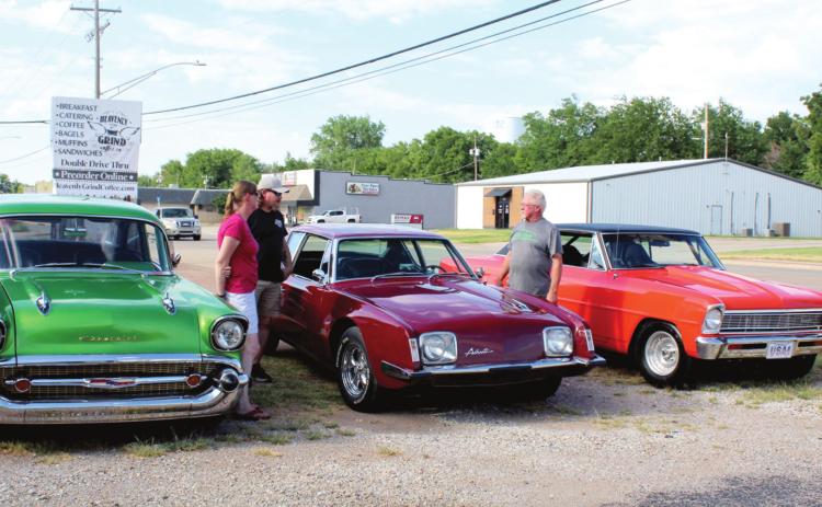 Danny Mellinger, of Tecumseh, third from left, talks with two visitors to the “Cruise the ‘Poo” event held on July 30 at the Brown Derby in Shawnee. Mellinger owns the 1964 Studebaker Avanti, in the middle. Also shown, left, is a 1950s Chevrolet owned by Sam Harden, of Tecumseh, and, right, a 1966 Chevy II owned by Andy Winkler, of Bethel. Mellinger said he was among the original “Kickapoo Riff Raff” who cruised Kickapoo and caused business owners to complain.