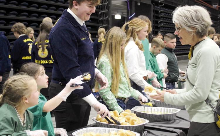 Tecumseh 4-H members Jessi Peacock and Adalyn Seaton and North Rock Creek FFA member Gus Goodson serve Delinda Curtis rolls and butter during the 34th Annual Pottawatomie County Junior Livestock Show Pig Roast and Trophy Auction in 2023. File photo