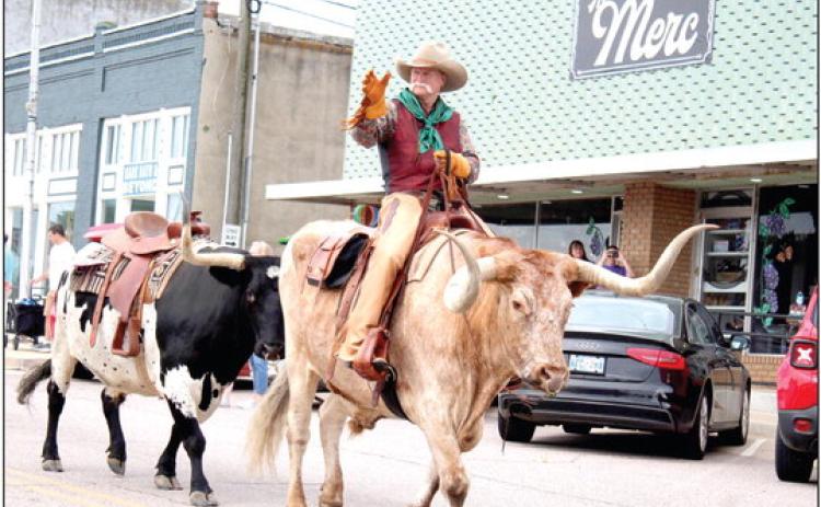 Roger Straka waves from his Longhorn bull, followed by another, in the McLoud Blackberry Festival parade on July 8. Countywide &amp; Sun/Natasha Dunagan
