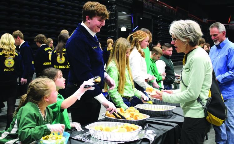 Tecumseh 4-H members Jessi Peacock and Adalyn Seaton and North Rock Creek FFA member Gus Goodson serve Delinda Curtis rolls and butter during the 34th Annual Pottawatomie County Junior Livestock Show Pig Roast and Trophy Auction on Feb. 6, 2023. Natasha Dunagan, Countywide &amp; Sun