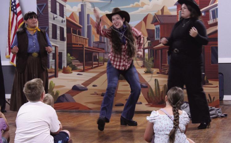 "Pop Magano," played by Savannah Gordon, demonstrates her skill with a lasso, as "Tam," played by Olivia Flores, left, and the "Queen of Knocked Sara Stro," played by Cheyenne Holland, watch during "The Magic Flute Goes West!" Presented by Painted Sky Opera as a McLoud Public Library event, the kid-friendly opera was performed at McLoud's American Legion on July 17. In August, Painted Sky Opera will present Mozart's "The Magic Flute" at the Civic Center in OKC.