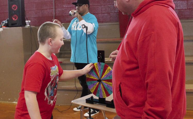 Earlsboro Elementary student Lethanial Hinesley spins the “family” sorting wheel as Principal Stacey Barton watches, Jan. 17. About 90 first- through fifth-graders participated in the positive behavior intervention ceremony where they spun a wheel to choose one of four families, slid down an inflatable slide and got a T-shirt. Each week, the family with the most points for good behavior will receive a reward. Countywide &amp; Sun/Natasha Dunagan